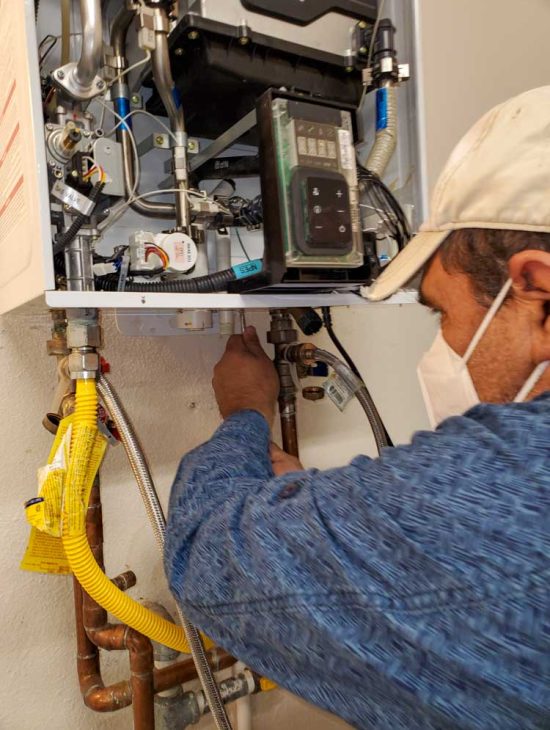 Technician Servicing a Modern Water Heater Technician adjusting valves on a modern water heater, showing intricate pipework and digital control units.