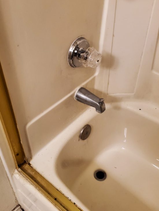 Basic Shower Plumbing Standard white shower stall with basic plumbing fixtures, showing signs of wear and needing potential upgrades.