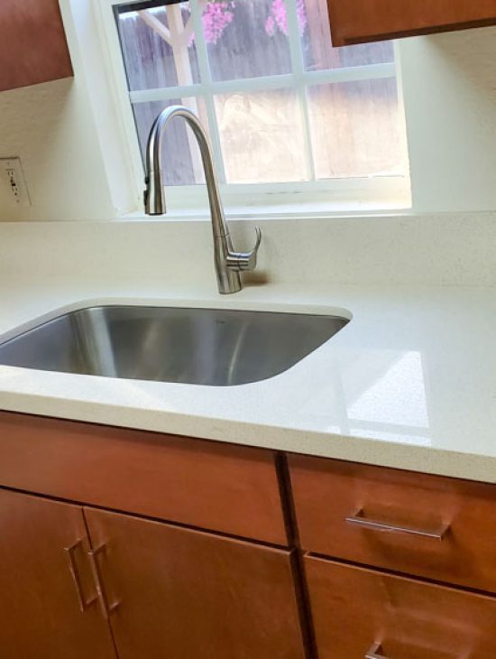 Streamlined Kitchen Plumbing Updated kitchen with modern appliances and a stainless steel sink, highlighting clean countertops and a minimalist design.