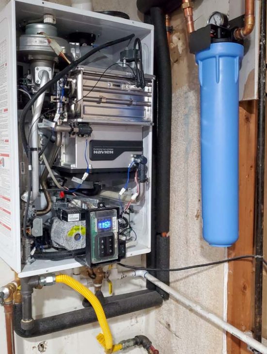 Modern Home Water Heating Solution Navien tankless water heater installed in a basement with a blue water filtration unit, showcasing a clean and organized setup.