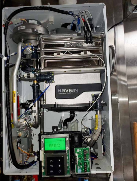 Detailed View of a High-Efficiency Boiler Open internal view of a Navien condensing boiler showing detailed piping and digital temperature controls.