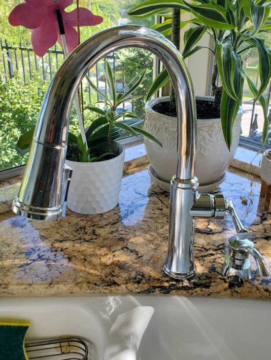 Elegant Kitchen Faucet over Sink Modern stainless steel faucet over a kitchen sink with a view of a window, showcasing a clean and stylish interior.