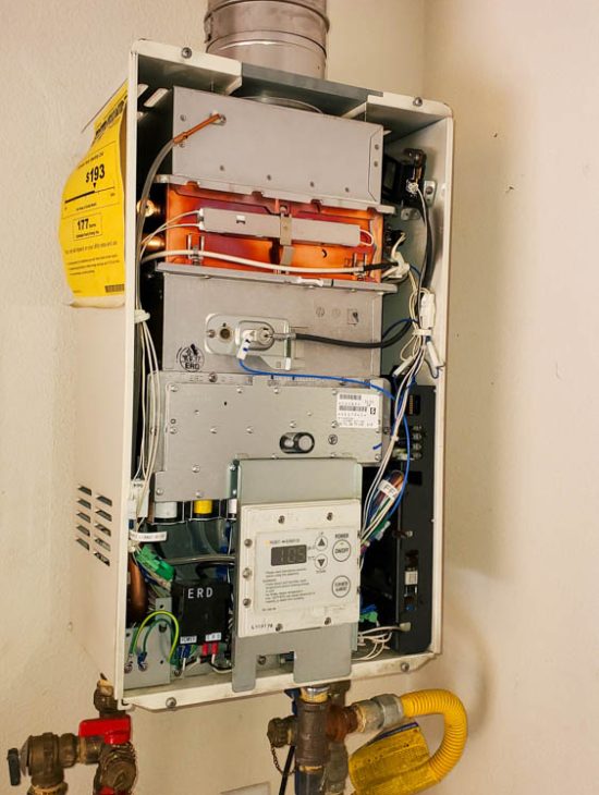 Tankless Water Heater Internal Components Open tankless water heater displaying its internal components and wiring, emphasizing detailed maintenance.