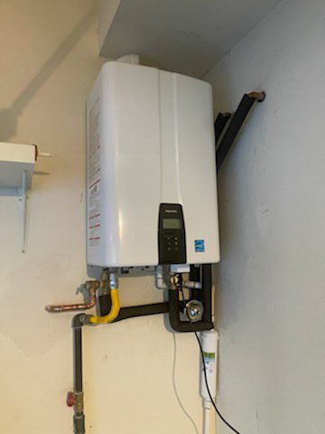 Space-Saving Water Heating Solution Compact white tankless water heater mounted on a light gray wall, connected to plumbing fixtures.