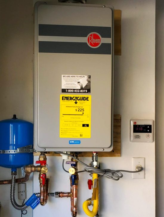 Efficient Tankless Water Heater Installation Modern Rheem tankless water heater installed in a utility room with energy guide and contact information displayed.